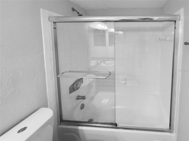 bathroom featuring shower / bath combination with glass door and toilet