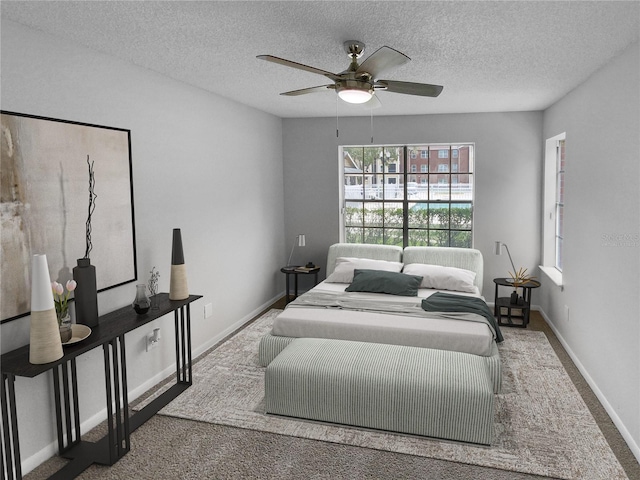 carpeted bedroom with ceiling fan and a textured ceiling