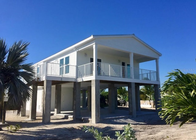 rear view of property with a carport, a patio area, driveway, and a balcony