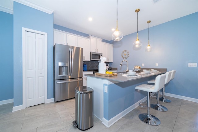 kitchen featuring tasteful backsplash, decorative light fixtures, a kitchen bar, white cabinets, and appliances with stainless steel finishes