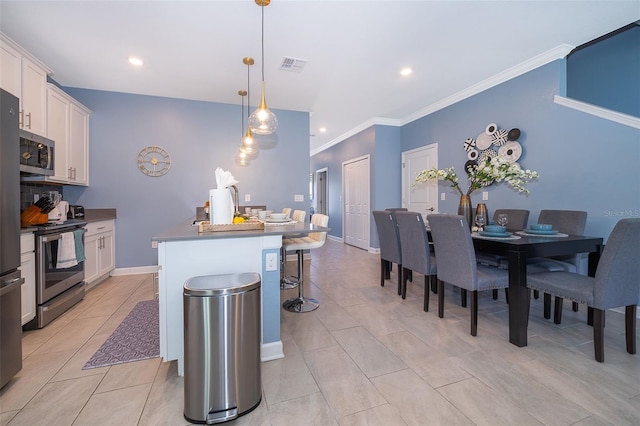 kitchen with an island with sink, pendant lighting, white cabinets, and stainless steel appliances