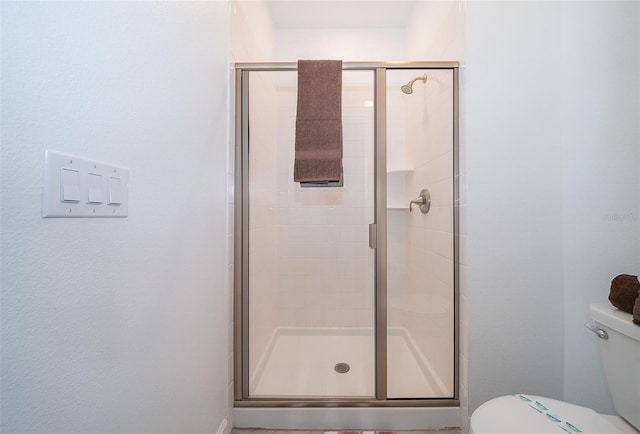 bathroom featuring walk in shower and toilet