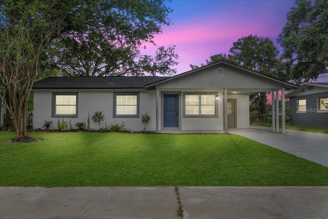 ranch-style home with a carport and a lawn