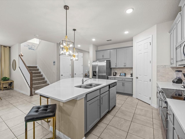 kitchen featuring decorative backsplash, a center island with sink, stainless steel appliances, and sink