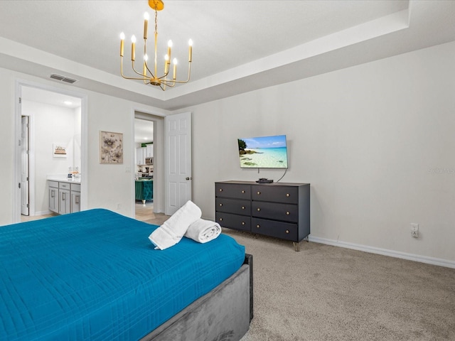 bedroom featuring a chandelier, a raised ceiling, light carpet, and ensuite bath