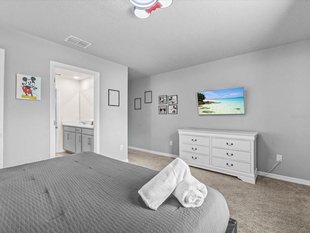 carpeted bedroom featuring ensuite bathroom and a textured ceiling