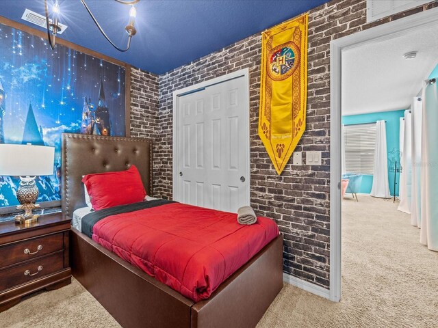 bedroom featuring a textured ceiling, light colored carpet, a closet, and brick wall