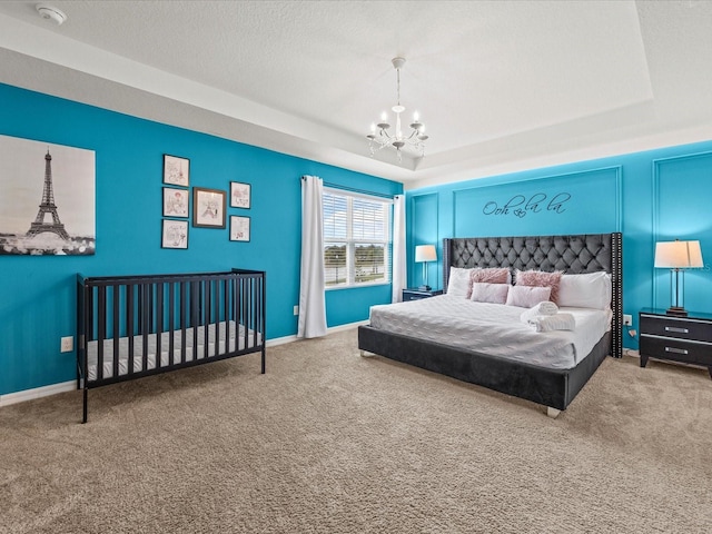 bedroom featuring carpet, a raised ceiling, a textured ceiling, and an inviting chandelier