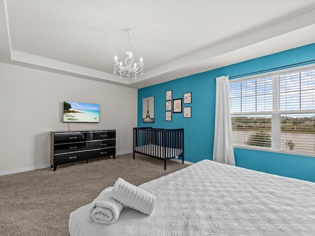 bedroom featuring carpet, a tray ceiling, and an inviting chandelier