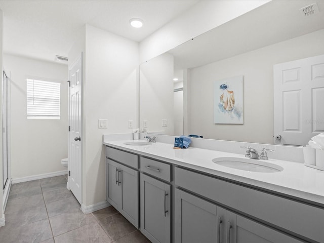 bathroom featuring tile patterned flooring, vanity, toilet, and a shower with door