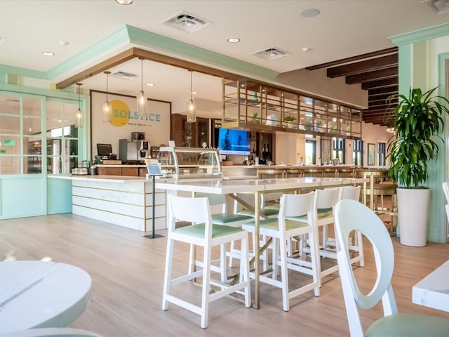 interior space featuring a kitchen breakfast bar, kitchen peninsula, hanging light fixtures, and light hardwood / wood-style floors