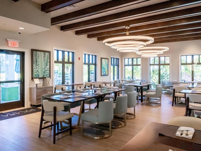 dining room with a chandelier, beam ceiling, and light hardwood / wood-style floors