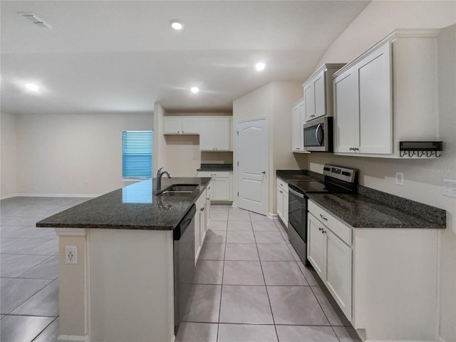 kitchen featuring stainless steel appliances, sink, dark stone countertops, white cabinetry, and an island with sink