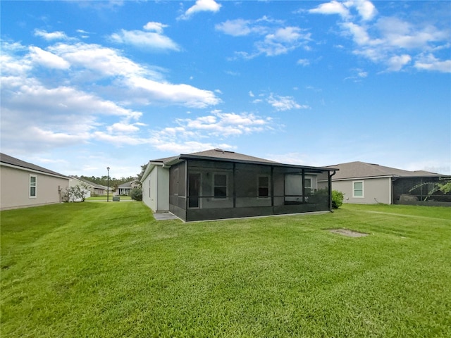 back of house featuring a sunroom and a lawn