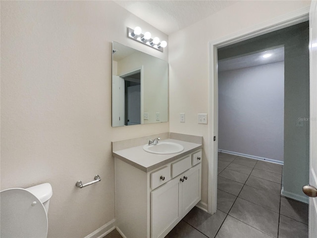 bathroom featuring tile patterned flooring, a textured ceiling, vanity, and toilet