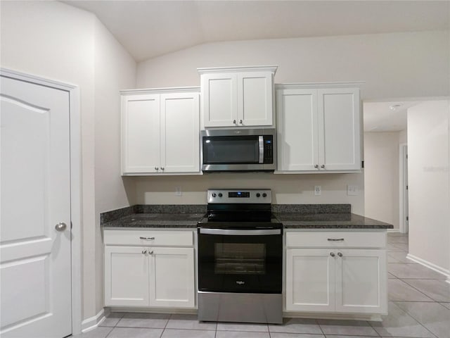 kitchen with white cabinets, dark stone countertops, stainless steel appliances, and vaulted ceiling