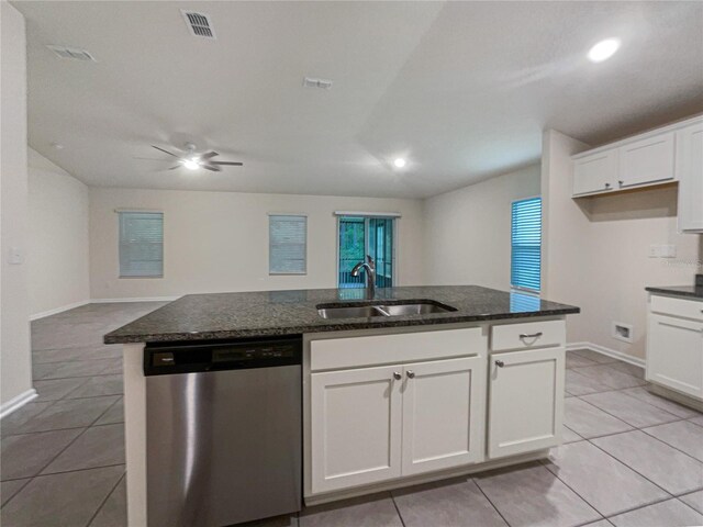 kitchen with dishwasher, dark stone counters, white cabinets, sink, and light tile patterned floors