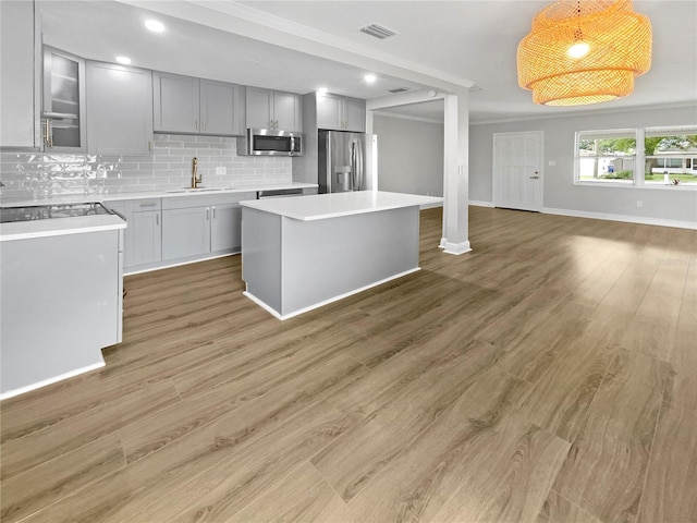 kitchen featuring decorative backsplash, appliances with stainless steel finishes, sink, decorative light fixtures, and a center island