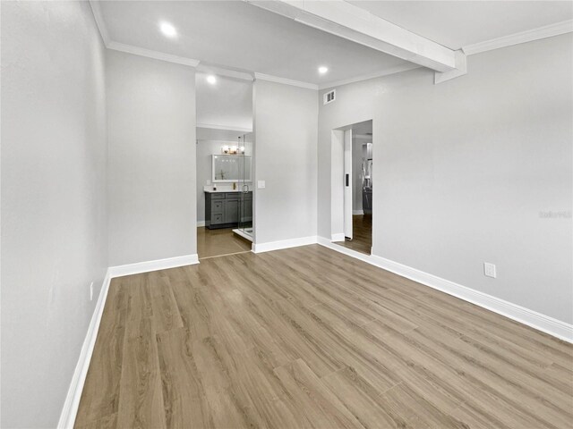 empty room with beam ceiling, light wood-type flooring, an inviting chandelier, and ornamental molding