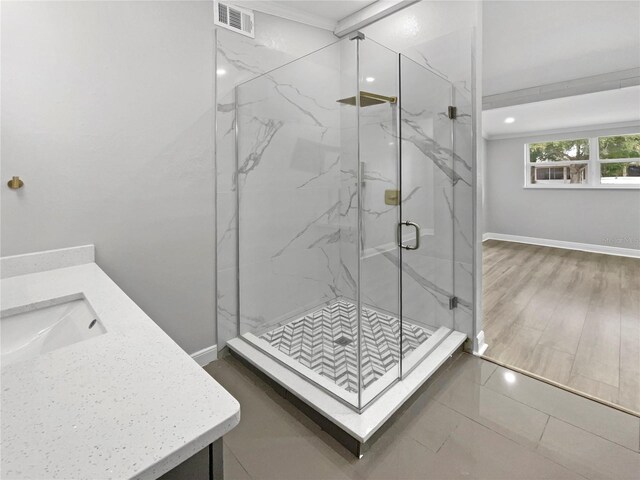 bathroom featuring vanity, a shower with shower door, and ornamental molding