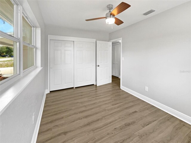 unfurnished bedroom featuring a closet, ceiling fan, and dark wood-type flooring