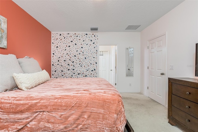 bedroom with light colored carpet and a textured ceiling