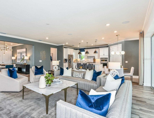 living room featuring light hardwood / wood-style flooring, a chandelier, and ornamental molding