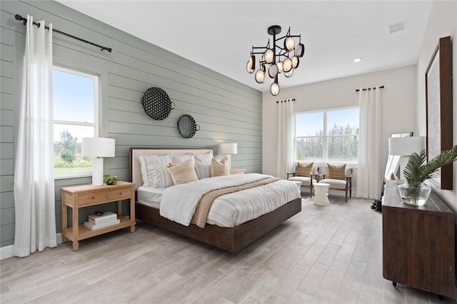 bedroom with wood walls, light hardwood / wood-style floors, and a notable chandelier