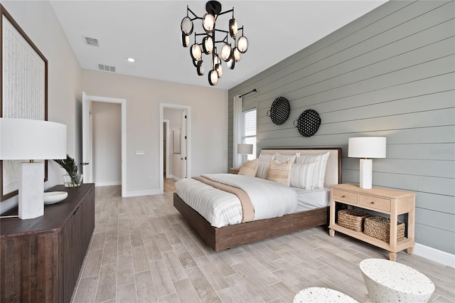 bedroom with light hardwood / wood-style flooring, wooden walls, and a chandelier