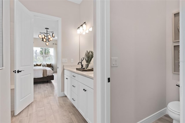 bathroom featuring vanity, hardwood / wood-style flooring, toilet, and an inviting chandelier