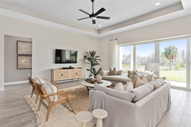 living room with ceiling fan and a raised ceiling