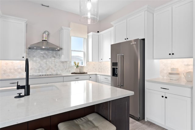 kitchen featuring white cabinets, high end refrigerator, light stone countertops, and a kitchen breakfast bar