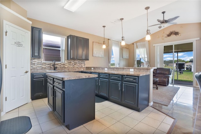 kitchen with pendant lighting, sink, lofted ceiling, backsplash, and a center island