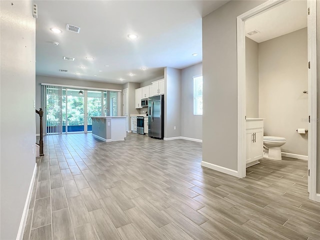 kitchen with appliances with stainless steel finishes, sink, white cabinets, a breakfast bar area, and an island with sink