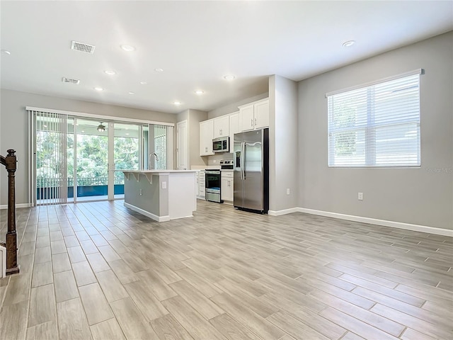 kitchen featuring a kitchen breakfast bar, white cabinetry, stainless steel appliances, and an island with sink