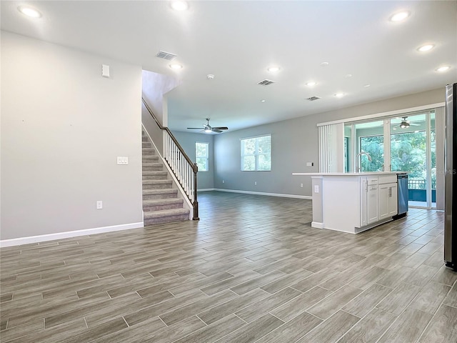 kitchen featuring ceiling fan, sink, white cabinetry, and an island with sink