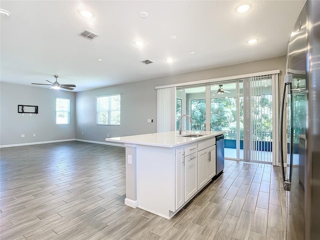 kitchen featuring ceiling fan, sink, stainless steel appliances, a center island with sink, and white cabinets