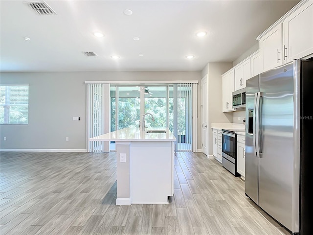 kitchen with sink, white cabinetry, stainless steel appliances, and a kitchen island with sink