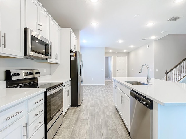 kitchen featuring white cabinets, sink, stainless steel appliances, and a kitchen island with sink