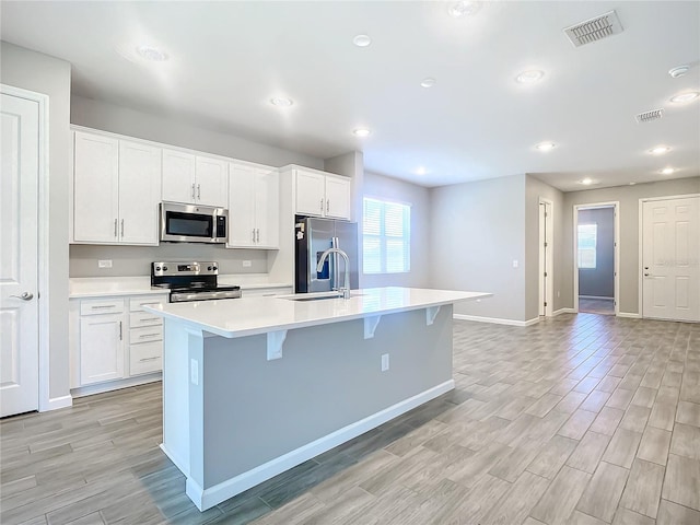 kitchen featuring a center island with sink, white cabinets, and appliances with stainless steel finishes