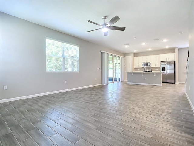 unfurnished living room with ceiling fan