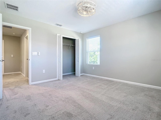 unfurnished bedroom featuring light carpet and a closet