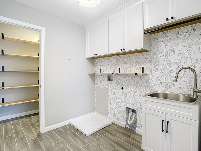 laundry area with hookup for an electric dryer, cabinets, and sink