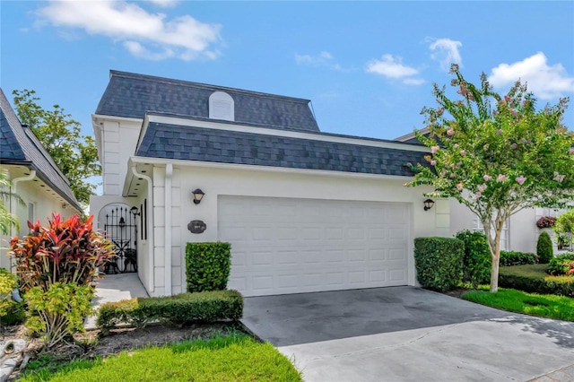 view of front of home with stucco siding, a shingled roof, mansard roof, a garage, and driveway