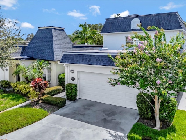 view of front of home featuring stucco siding, a shingled roof, mansard roof, concrete driveway, and a garage