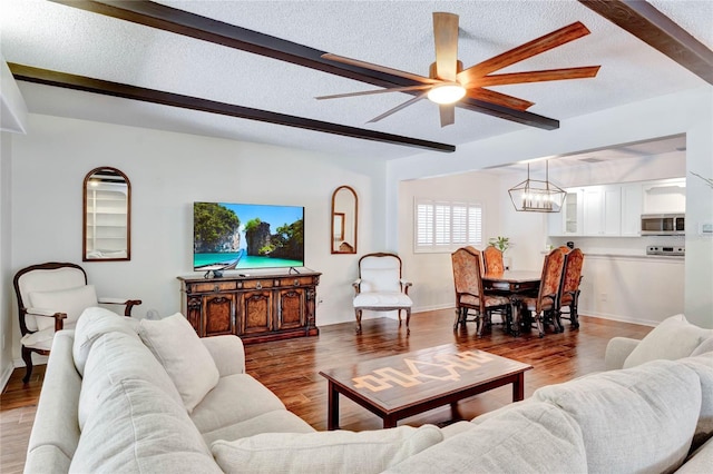 living room with a textured ceiling, wood finished floors, and beam ceiling