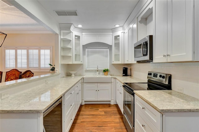 kitchen featuring stainless steel appliances, a sink, glass insert cabinets, and white cabinets