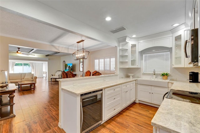 kitchen with a peninsula, white cabinetry, visible vents, and glass insert cabinets