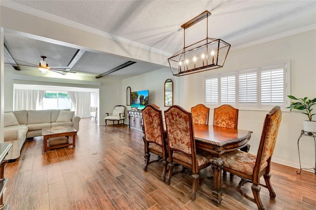 dining area with ornamental molding, ceiling fan with notable chandelier, a textured ceiling, and wood finished floors