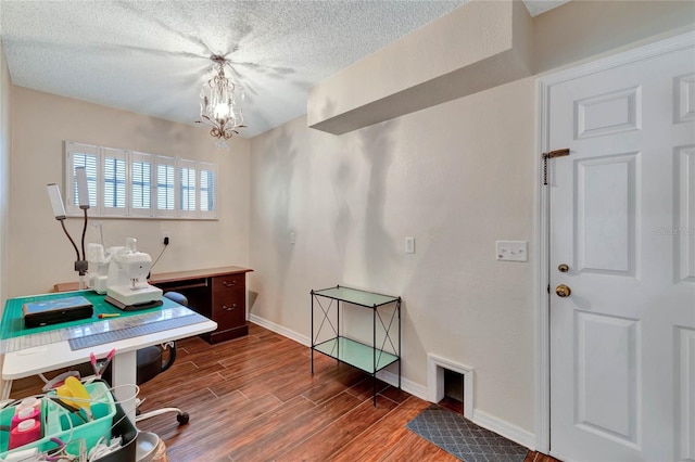 office space featuring a notable chandelier, a textured ceiling, baseboards, and wood finished floors